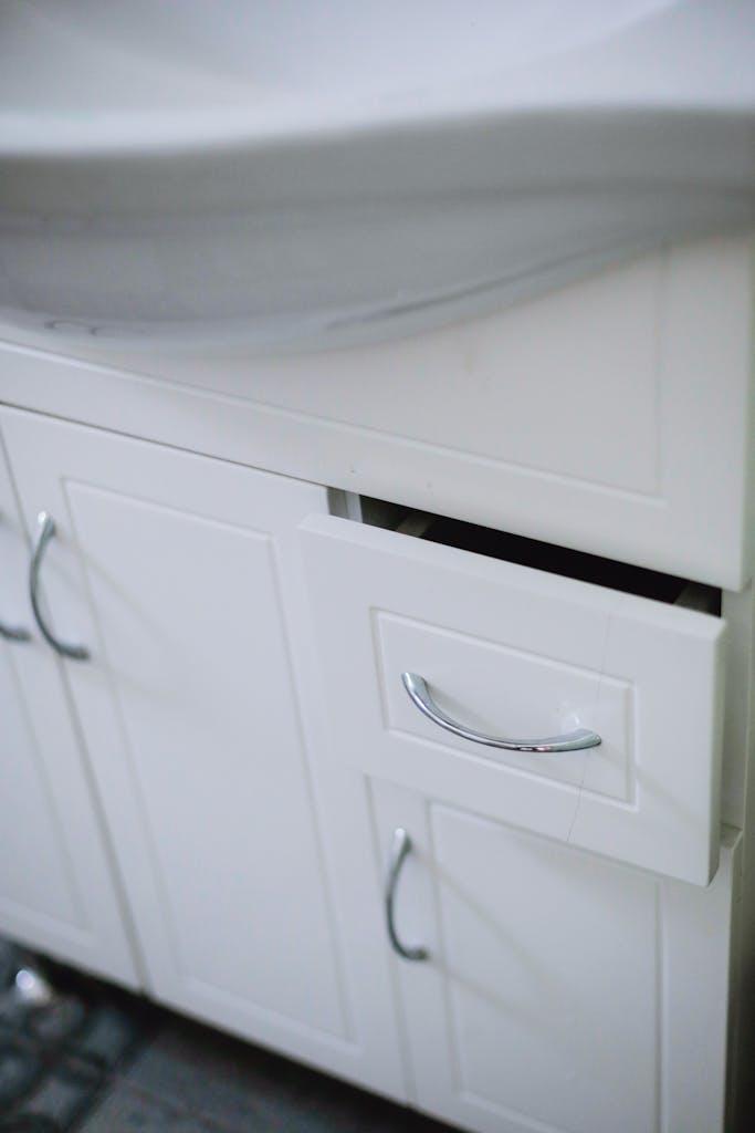 Close-up of a sleek white bathroom cabinet with drawer and sink in modern design.