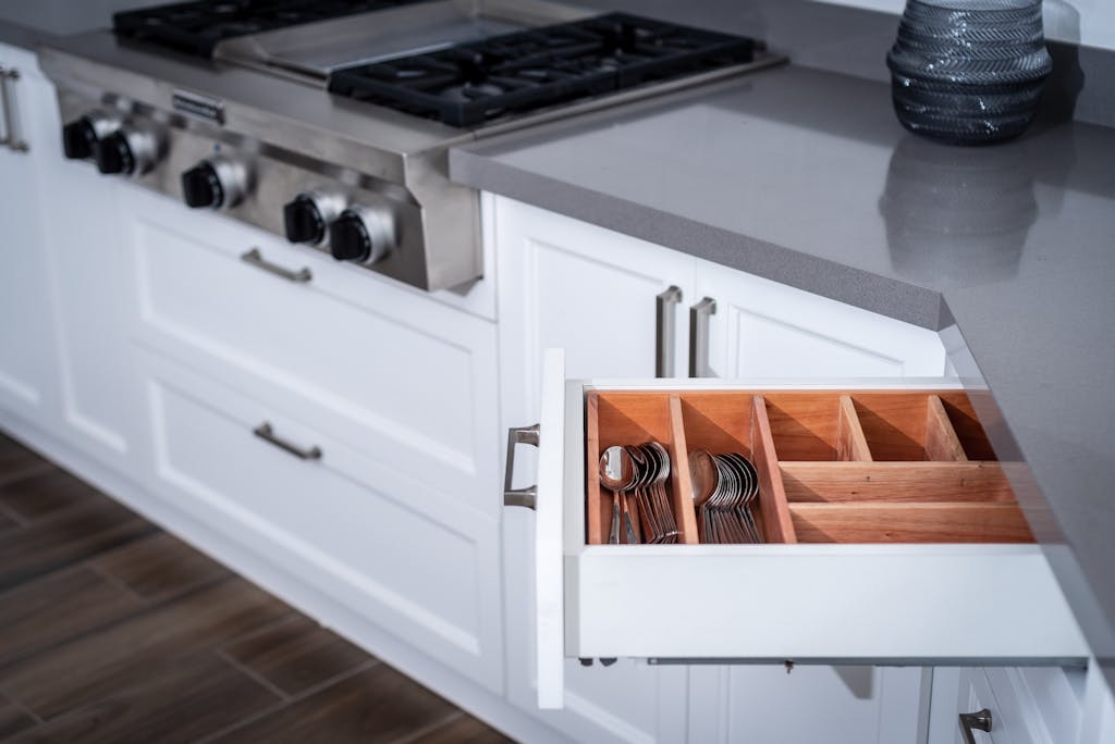 Sleek modern kitchen showcasing a neatly organized drawer next to a stainless steel stove.
